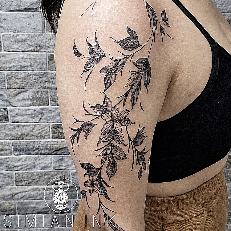 Tatuaje de enredadera de hojas en línea fina y sombra que sube por el hombro y la espalda