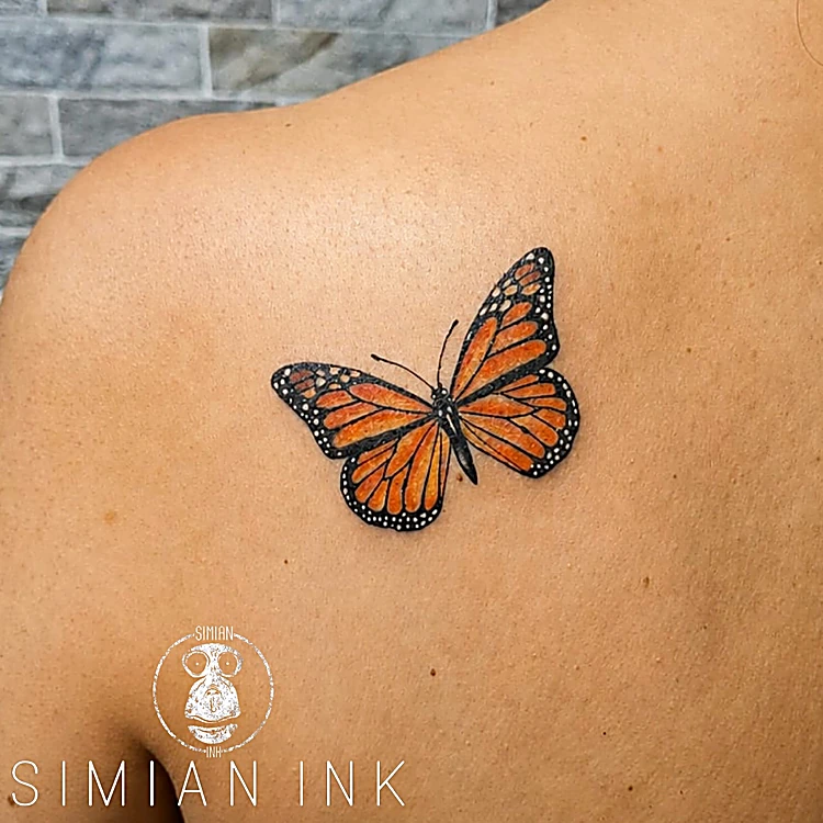 Tatuaje realista de mariposa monarca naranja sobre el omóplato